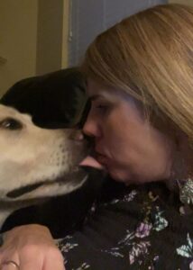 Spike the white lab kissing Julie Maloney on the nose.